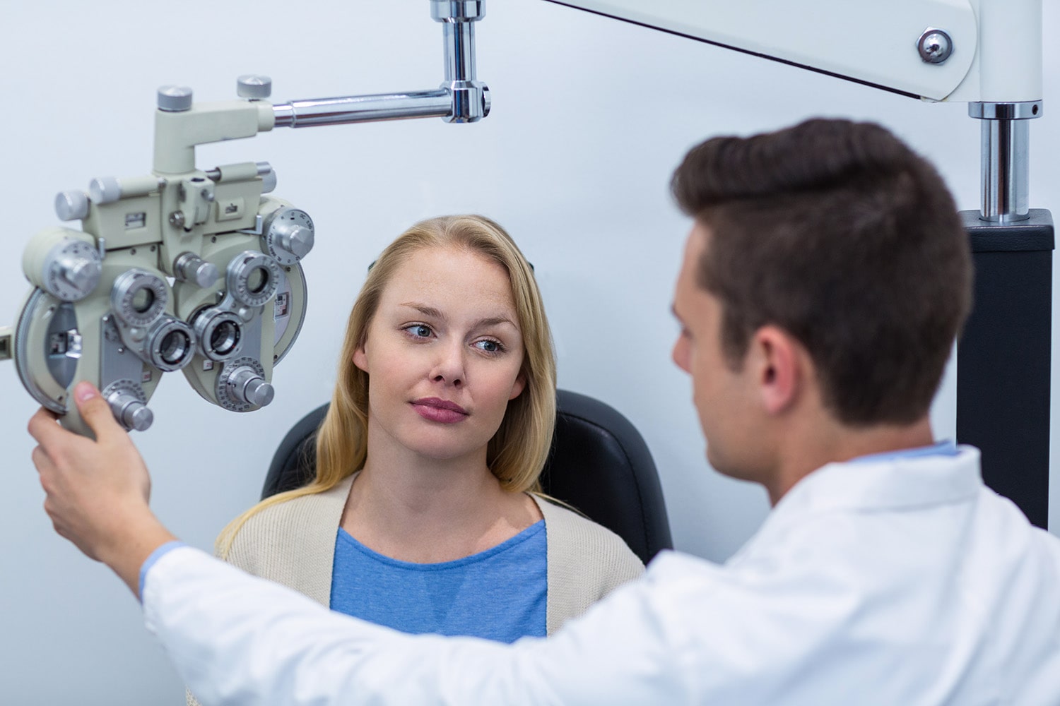 Optometrist interacting with female patient while eye test in ophthalmology clinic